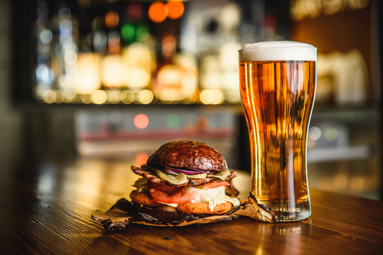 Hamburger and light beer on a pub background.