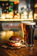 Hamburger and dark light beer on a pub background.