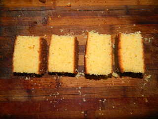On a wooden board lined coarsely chopped pieces of fresh baked yellow cake from corn flour.On a wooden board lined coarsely chopped pieces of fresh baked yellow cake from corn flour.
