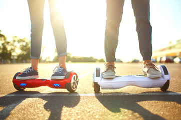 young man and woman riding on the Hoverboard in the park. content technologies. a new movement. Close Up of Dual Wheel Self Balancing Electric Skateboard Smart. on electrical scooter outdoors


