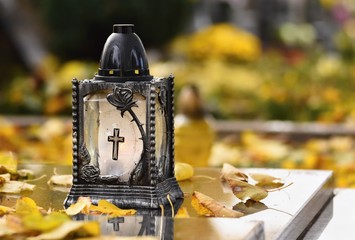 Beautiful autumn concept to the cemetery and Halloween. Candle in a lantern on the grave....