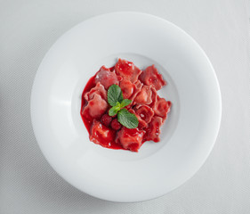 sweet dumplings with raspberries on a white plate