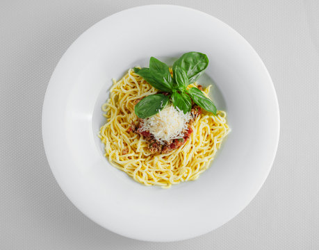 Spaghetti With Bolognese Sauce And Cheese On A White Plate. View From Above