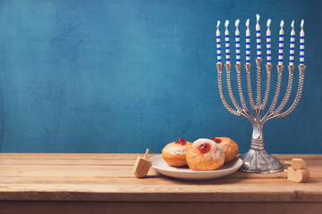 Hanukkah holiday sufganiyot and menorah on wooden table over vintage background © maglara