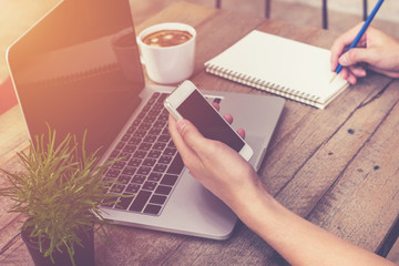 young business man hand holding phone and using laptop computer