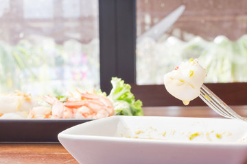 selective focus Boiled squid dipping in spicy chili sauce by fork,