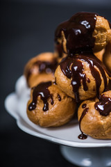 Stack of profiteroles eclairs with dark melted chocolate