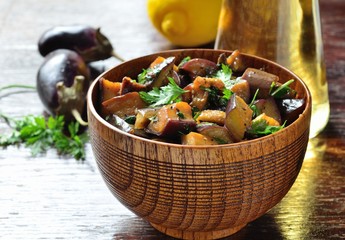 Appetizer of eggplant with herbs and spicy sauce in a wooden bowl