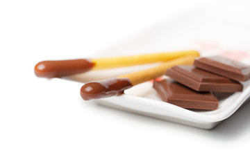 Biscuit cookie sticks in cacao coating with milk chocolate chunk