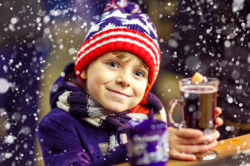 Little kid boy with hot chocolate on Christmas market