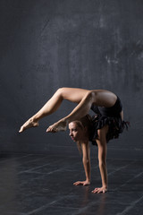 Woman dancer make handstand in dark studio