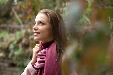 Portrait of young woman in pink topcoat at autumn day