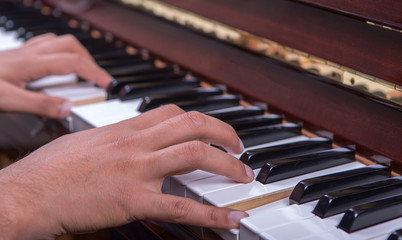 Obraz premium Man playing piano with both hands side view closeup