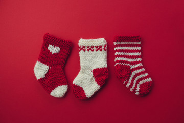 Mini Christmas Stockings.Three red and white wool Christmas stockings on red background.