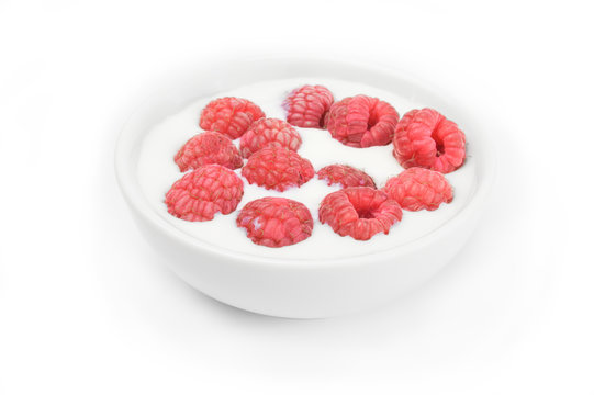 Ripe raspberry into milk in the bowl on white
