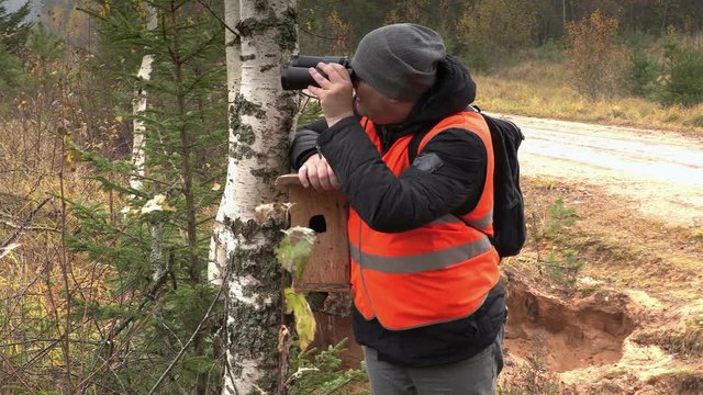 Ornithologist using binoculars in forest