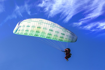 Tandem Paragliding on background of blue summer sky and white cl