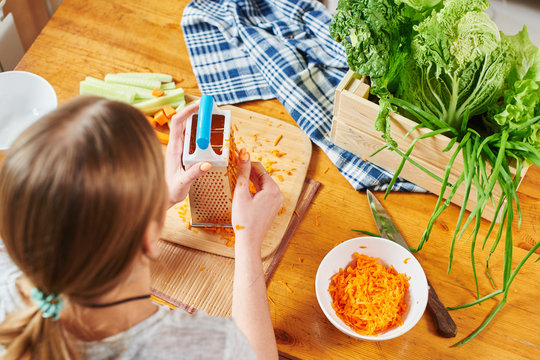 Girl grate the carrots on a wooden Board