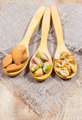 Almonds, walnuts and pistachio on a wooden spoon.