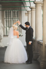 Lovely happy wedding couple, bride with long white dress posing in beautiful city
