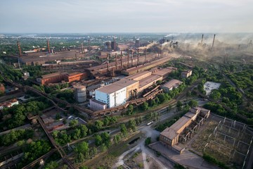 Fototapeta premium Industrial landscape in Ukraine. Steel factory with smog at sunset. Pipes with smoke. Metallurgical plant. steelworks, iron works. Heavy industry. Ecology problems, atmospheric pollutants.
