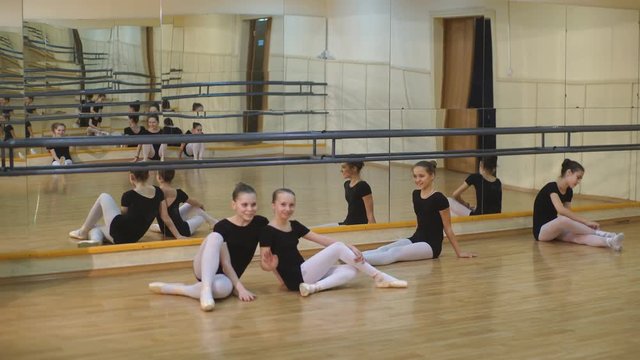 group of eight little ballerinas sitting on the floor