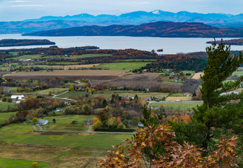 view from Mount Philo of rural Vermont farm valley in autumn  with Lake Champlain and the snow...