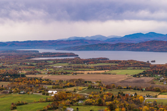 view of rural Vermont farm valley in autumn  with Lake Champlain and the Adirondack Mountains  in distance 
