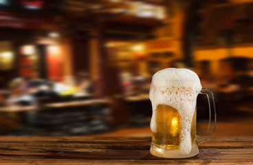 cold mug of beer with foam on the background of the street