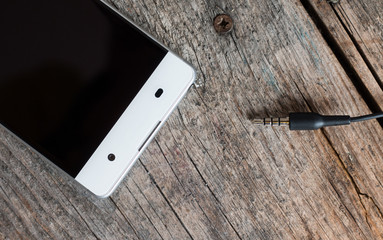 Klinkenstecker / Audiostecker, Smartphone weiß auf Holzuntergrund