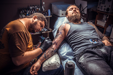 Tattooer showing process of making a tattoo in tattoo studio