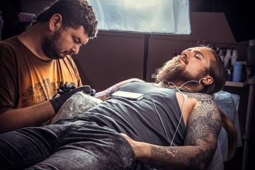 Tattooer showing process of making a tattoo in tatoo salon