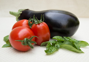 Three Ripe Roma Tomatoes with Eggplant and Sprigs of Fresh Basil