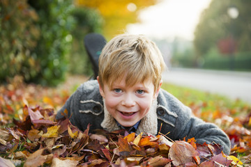 smiling boy in yellow and red leaves