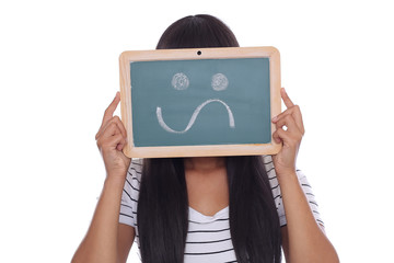 Attraktive junge Frau hält Tafel mit neutralem Smiley Zeichen vor ihr Gesicht