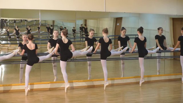 Young ballet dancers stands near the ballet barre at the ballet hall
