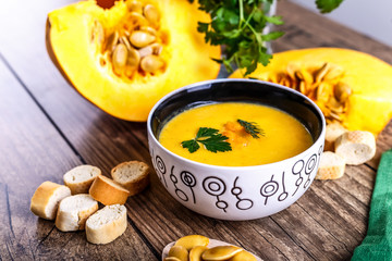 Cream pumpkin soup with fresh herbs and crackers on dark wooden background. Healthy food. Selective focus.