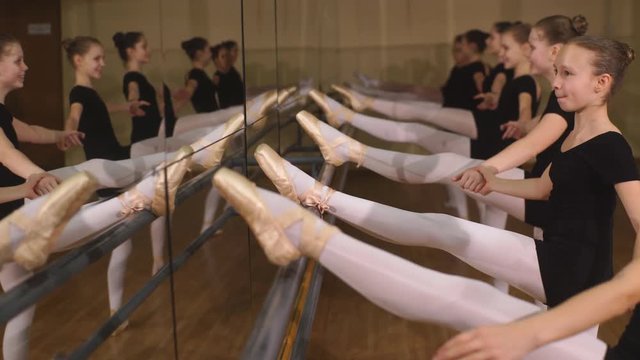a group of girls with their leg up in a barre during a ballet class at school