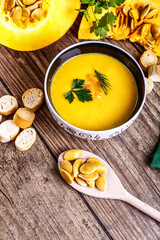 Cream pumpkin soup with fresh herbs and crackers on dark wooden background. Healthy food. Selective focus. Top view.