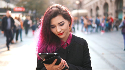 Hipster girl using a tablet pc in the street