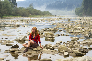 woman resting on the rocks in the middle of mountain lake