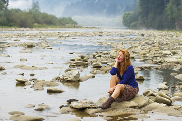 woman resting on the rocks in the middle of mountain lake