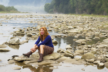 woman resting on the rocks in the middle of mountain lake