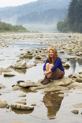woman resting on the rocks in the middle of mountain lake