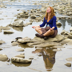woman meditating sitting on stone in quiet location