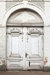 Closed old white wooden door with a round arch