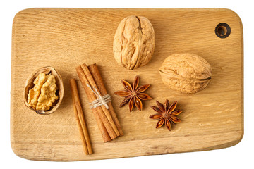 Walnuts, cinnamon sticks and star anises on wooden board.