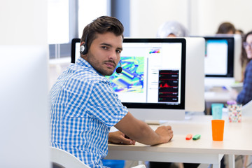 Man Working At Desk In Busy Creative Office