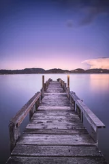 Photo sur Plexiglas Jetée Jetée ou jetée en bois sur un coucher de soleil sur un lac bleu. Italie