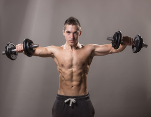 Fototapeta na wymiar young man bodybuilder looking down, dumbbells exercise.